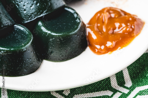 Pinoy Snack-Black Puto cuchinta or kutsinta with caramel dip and coconut shavings on the side is a type of steamed rice cake (puto) found throughout the Philippines (close up) photo