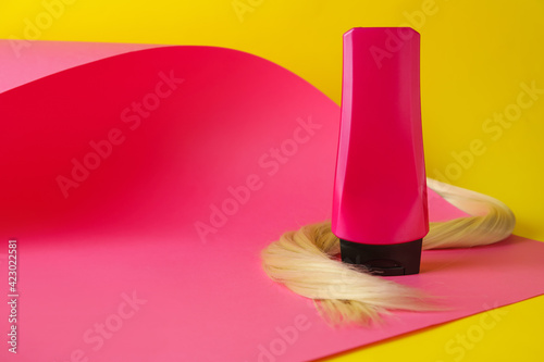 Bottle of hair shampoo and strand on color background © Pixel-Shot