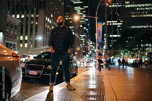 Cool stylish man standing on pavement of night city