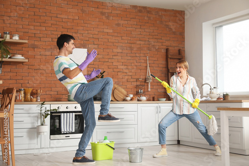 Young couple having fun while cleaning their kitchen