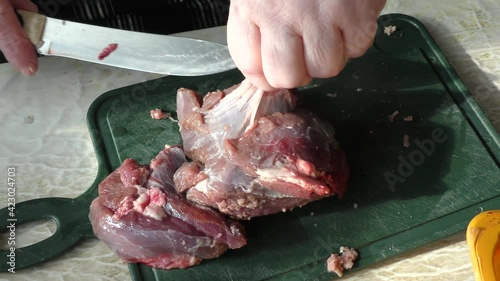 the cook cuts raw deer meat with a knife.  healthy food concept