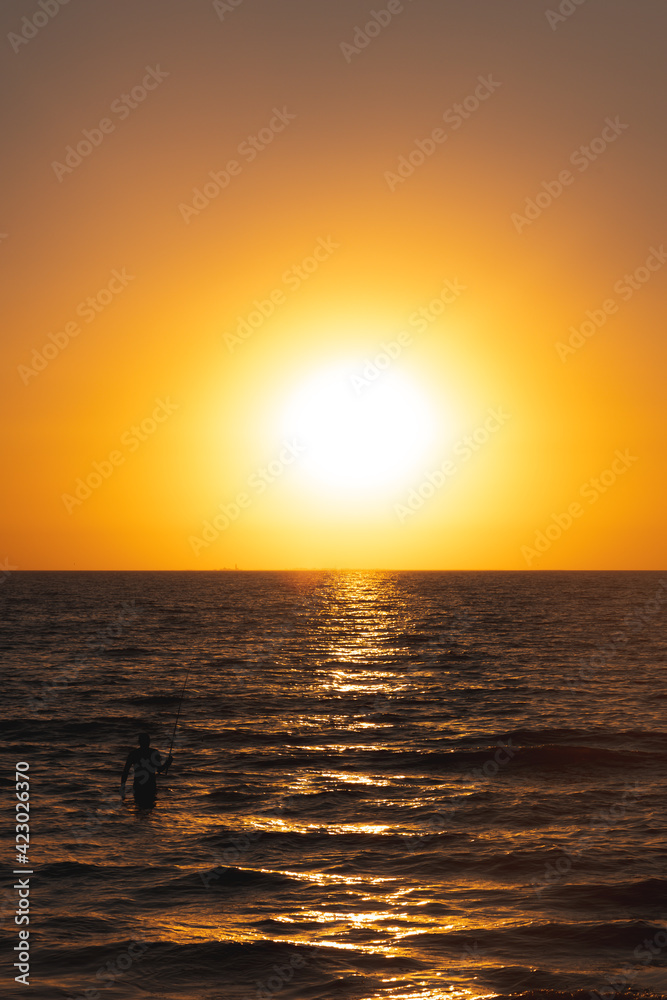 Fisherman catches fish in the sea at sunrise or sunset Fisherman catches fish in the sea at sunrise or sunset