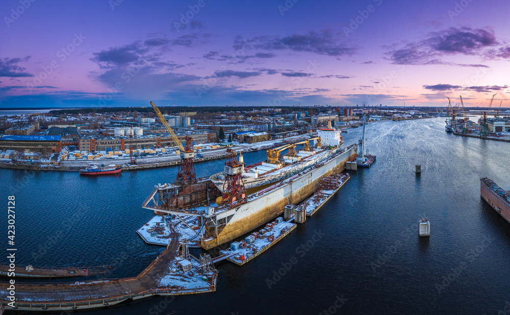 Ship repair and maintenance docks in beautiful sunset colors. Giant cargo vessel being repaired at dockyard in Riga. 