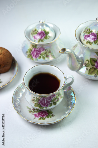 A cup of tea on a white tablecloth. Tea with muffins. Light breakfast. White tea set with flowers.