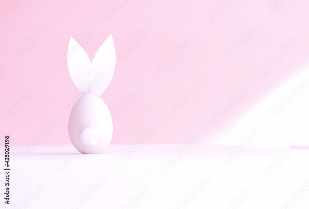 Easter egg in the form of a rabbit on a pink background, rear view