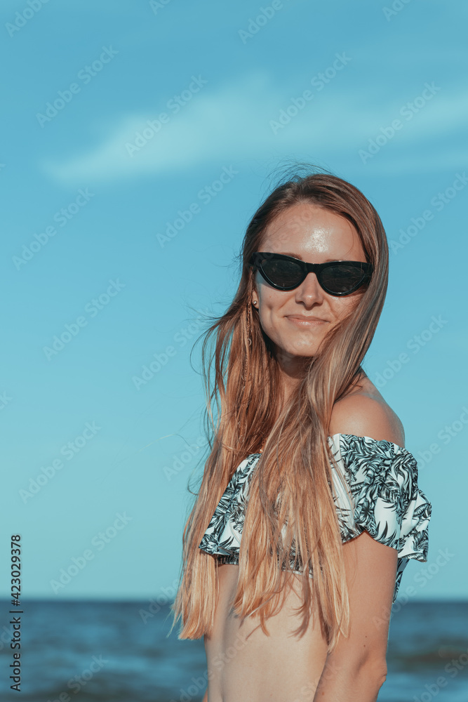 girl in a swimsuit posing against a background of water. happy woman smiling on vacation girl in a swimsuit posing against a background of water. happy woman smiling on vacation