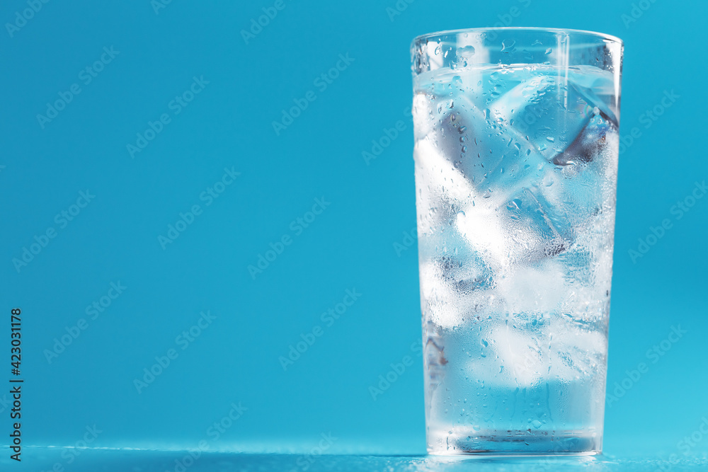 A glass with ice and clean water on a blue background. A glass with ice and clean water on a blue background.