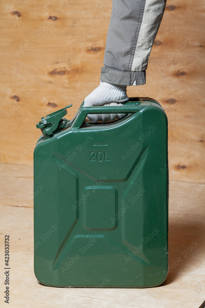Hand holds iron canister on wooden background