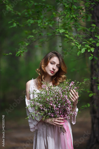 beautiful girl in a pink lace dress walks in the park with a bouquet of pink flowers, bride in boho style