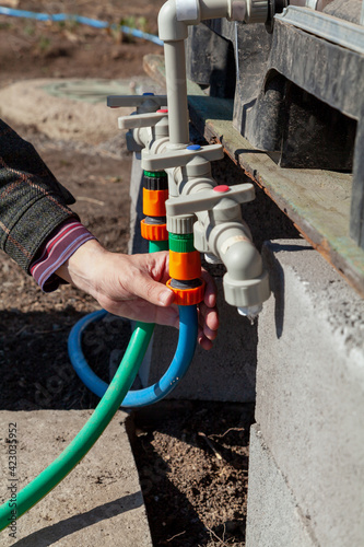 Hand winds hose on plastic irrigation system