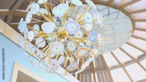 Stylish fashionable unusual chandelier made of yellow gold metal and cut stones. Chandelier under the dome. Lighting fixture.