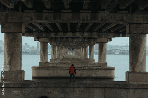 guy rufer climbed under the bridge with water. a man is photographed against the background of reinforced concrete bridge beams / парень руфер залез под мост с водой. мужчина фотографируется на фоне 