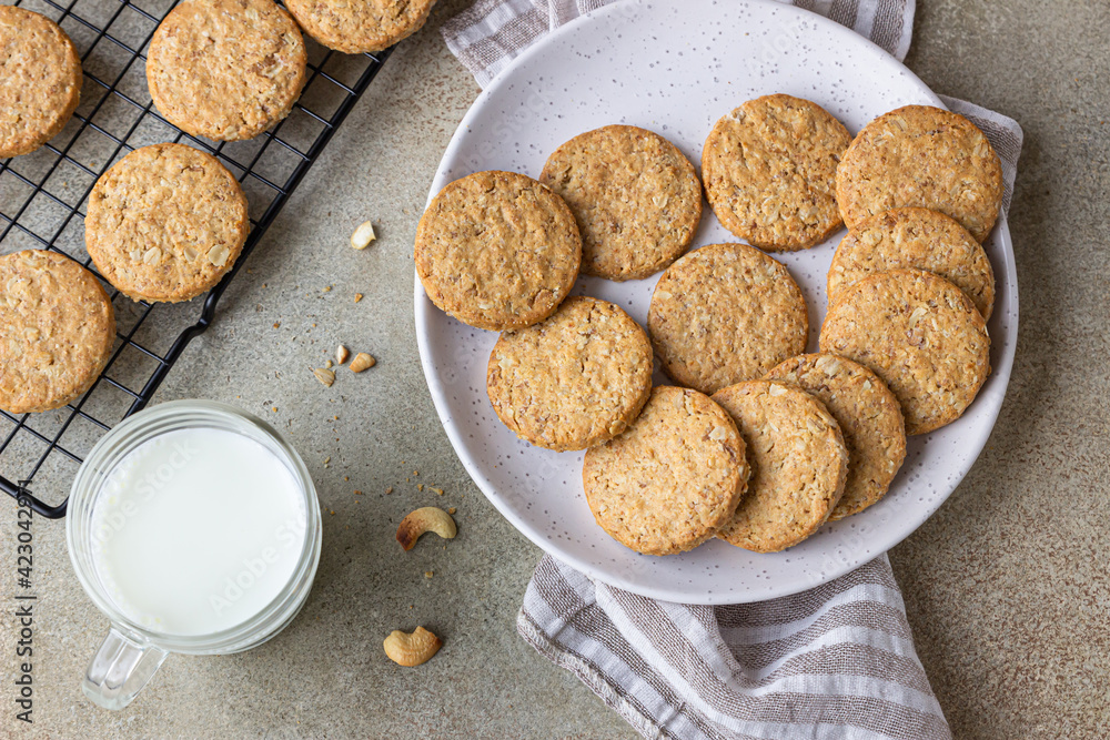 Healthy oatmeal cookies with cereals, seeds and nuts with a cup of milk on concrete background. Diet vegan cookies. Top view. Healthy oatmeal cookies with cereals, seeds and nuts with a cup of milk on concrete background. Diet vegan cookies. Top view.