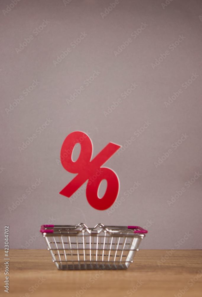 Φωτογραφία Shopping cart from the supermarket with sign percent over gray paper background