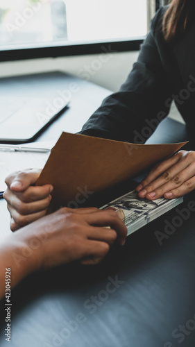 Businesswoman hand holding bribe money to government officials sign contracts for business projects, put money under envelope, ideas of corruption and anti-bribery