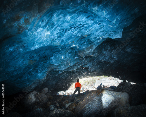 teenager under the textured dome of blue ice, ice inside the Alibeksky glacier in Dombai