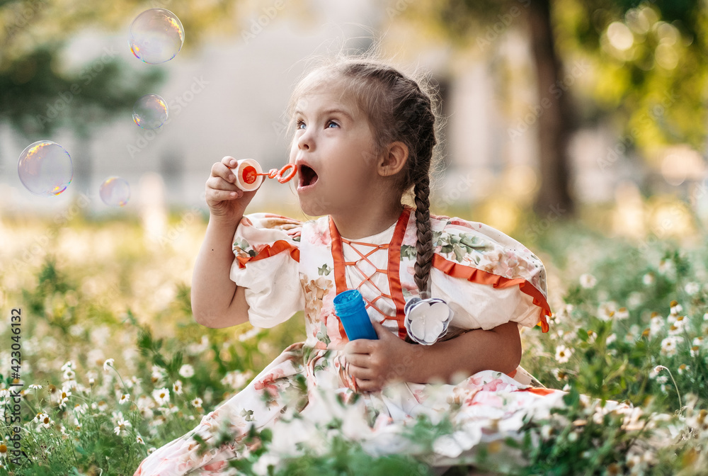 A girl with Down syndrome blows bubbles. The daily life of a child with disabilities. Chromosomal genetic disorder in a child. A girl with Down syndrome blows bubbles. The daily life of a child with disabilities. Chromosomal genetic disorder in a child.