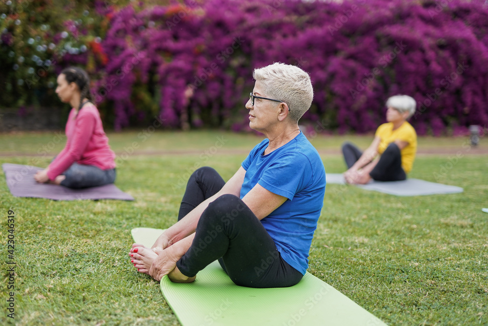 Multi generational women doing yoga at park sitting with social distance for coronavirus outbreak - Healthy lifestyle and sport Multi generational women doing yoga at park sitting with social distance for coronavirus outbreak - Healthy lifestyle and sport