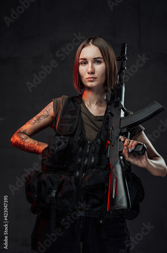 Seductive military girl holding rifle in dark background