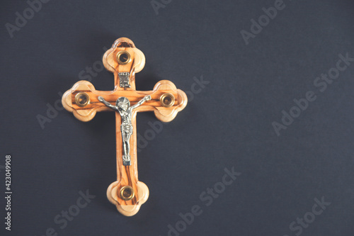 Christian cross on wooden table against black background. Religion concept © Vahe