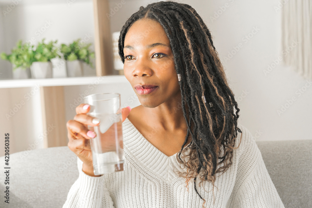 A Casual smiling woman drinking some water at home A Casual smiling woman drinking some water at home