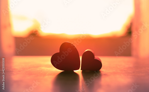 Two hearts on window side by side facing the sunset. Love and relationships concept. 