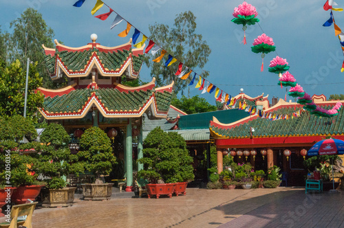 Vietnamesiche Tempelanlage , dekoriert mit Papierblumen. Leuchtende Farbe vor einem strahlend blauen Himmel