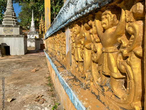 Teilansicht eine steinerden Balustrade, verziert mit vergoldeten Affen-Figuren. Kleine Tempel im Hintergrund. photo