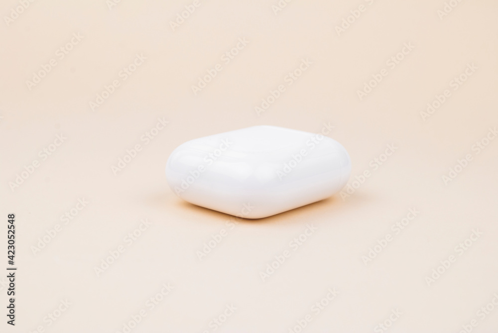 Wireless headphones in a white case on a nice pastel background Wireless headphones in a white case on a nice pastel background