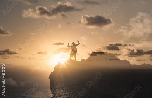 Strong man flexing on top of a mountain reaching his goals. Sport motivation, and winning concept.  © kieferpix