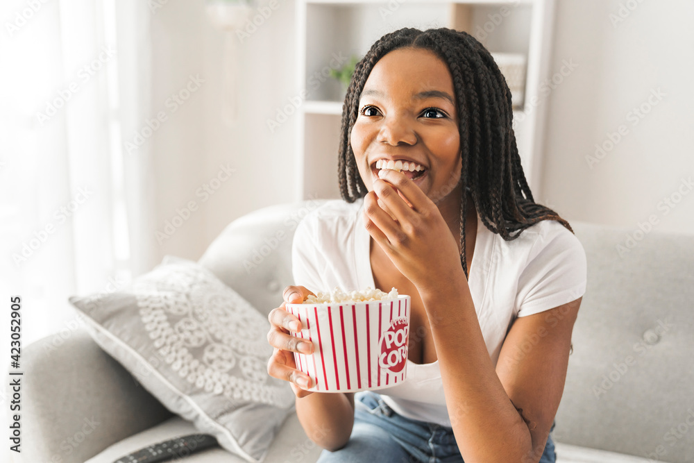 Portrait of teenager watching tv with pop corn on hand