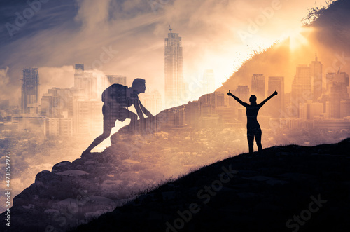 Silhouette of a person climbing to the top of a mountain. Female with arms up to the sky. Strong man, and woman, Winning, success , inspiration and life goals concept. 