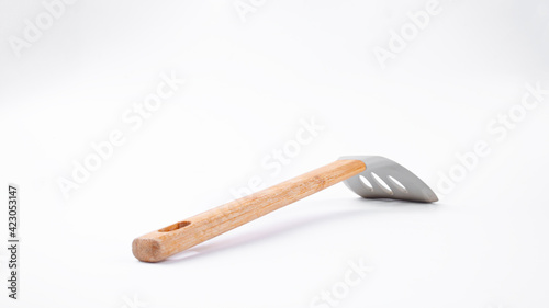 Kitchen spatula with wooden handle on a white background. Side view of kitchen spatula.