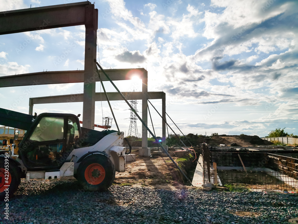 Obraz premium excavator on new construction site, in the background the blue sky and sun