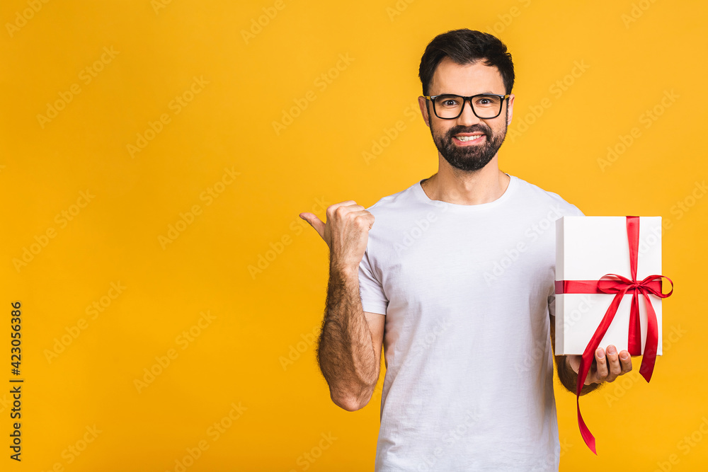 Wonderful gift! Adorable photo of attractive bearded man with beautiful smile holding birthday present box isolated over yellow background. Wonderful gift! Adorable photo of attractive bearded man with beautiful smile holding birthday present box isolated over yellow background.