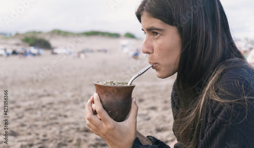 Young woman drinking traditional Argentinian yerba mate at the beach.