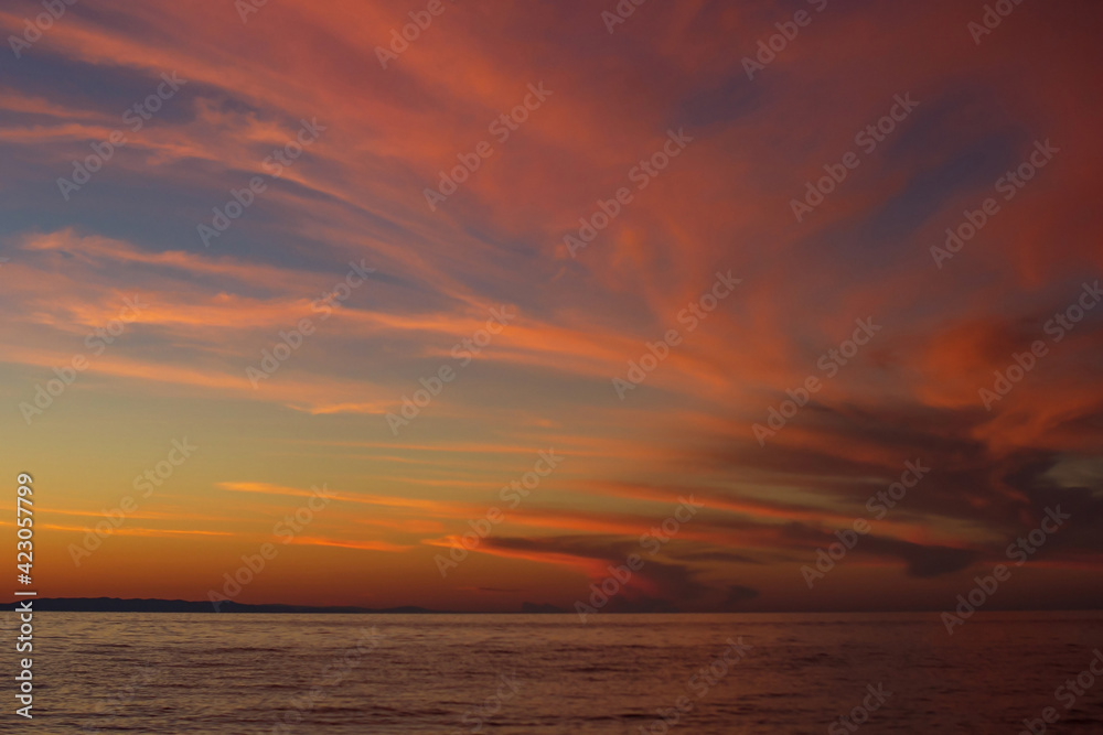 Dramatic red clouds after sunset in dusk on Lake Baikal, beautiful scenic seascape, dark moody style