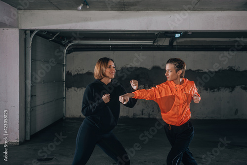 Two female athletes showing technical skills while practicing fighting in a garage