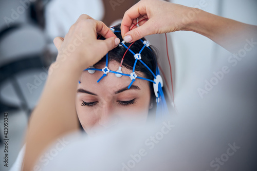 Qualified neurophysiologist placing the electrodes on the female scalp