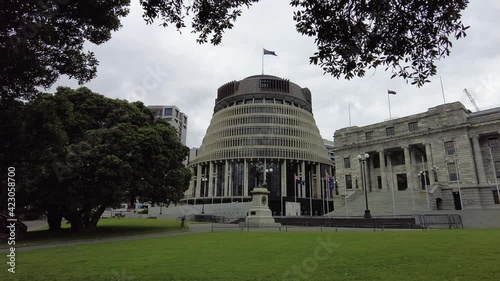 The Beehive Parliament Buildings Wellington New Zealand static image with flags blowing cloudy day photo