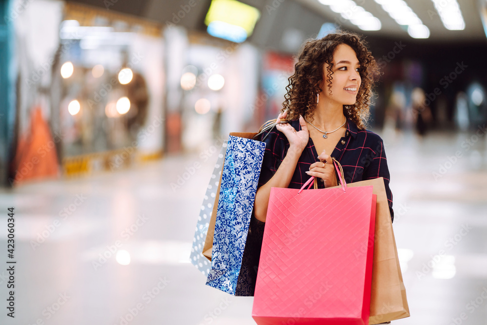 Young woman after shopping with shopping bags walks in the mall. Spring shoopping. Purchases, black friday, discounts, sale concept. Young woman after shopping with shopping bags walks in the mall. Spring shoopping. Purchases, black friday, discounts, sale concept.