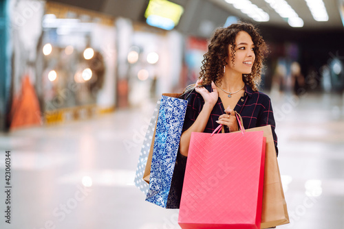 Young woman after shopping with shopping bags walks in the mall. Spring shoopping. Purchases, black friday, discounts, sale concept.