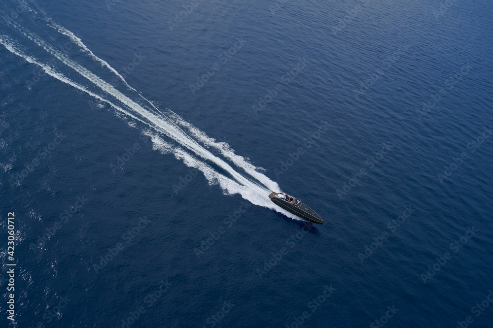 Drone view of a dark blue boat. Aerial view luxury motor boat. Drone view of a boat the blue clear waters. Large speed boat moving at high speed side view. Drone view of a dark blue boat. Aerial view luxury motor boat. Drone view of a boat the blue clear waters. Large speed boat moving at high speed side view.