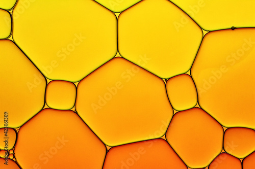 Bright Hot Background Closeup of Oil Drops in Water. Abstract Art Macro Photo of Liquid Surface with Gradient Yellow and Orange Bubbles.