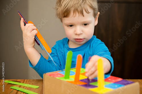 Montessori implement. Sorting by the colors. DIY at home from cardboard box and ice-cream sticks. Easy 5 minute craft. Early preshool eduaction for toddlers. photo