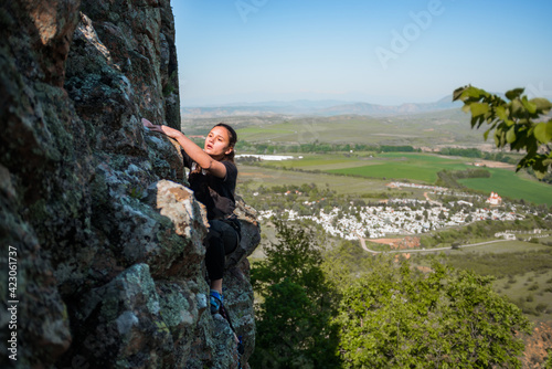 Young woman beginner climbing vertical cliff