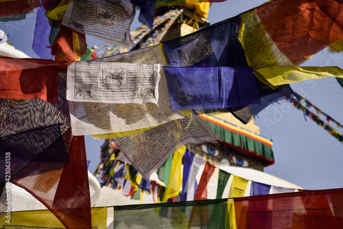 Close-up of colorful prayer flags hanging in front of Boudhanath stupa. Shallow depth of field. Kathmandu, Nepal.