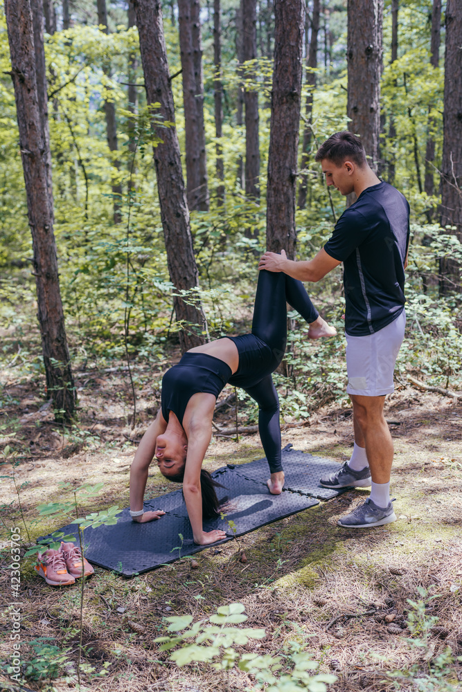 Young active couple doing stretching exercises in the woods on a yoga mat after jogging and running