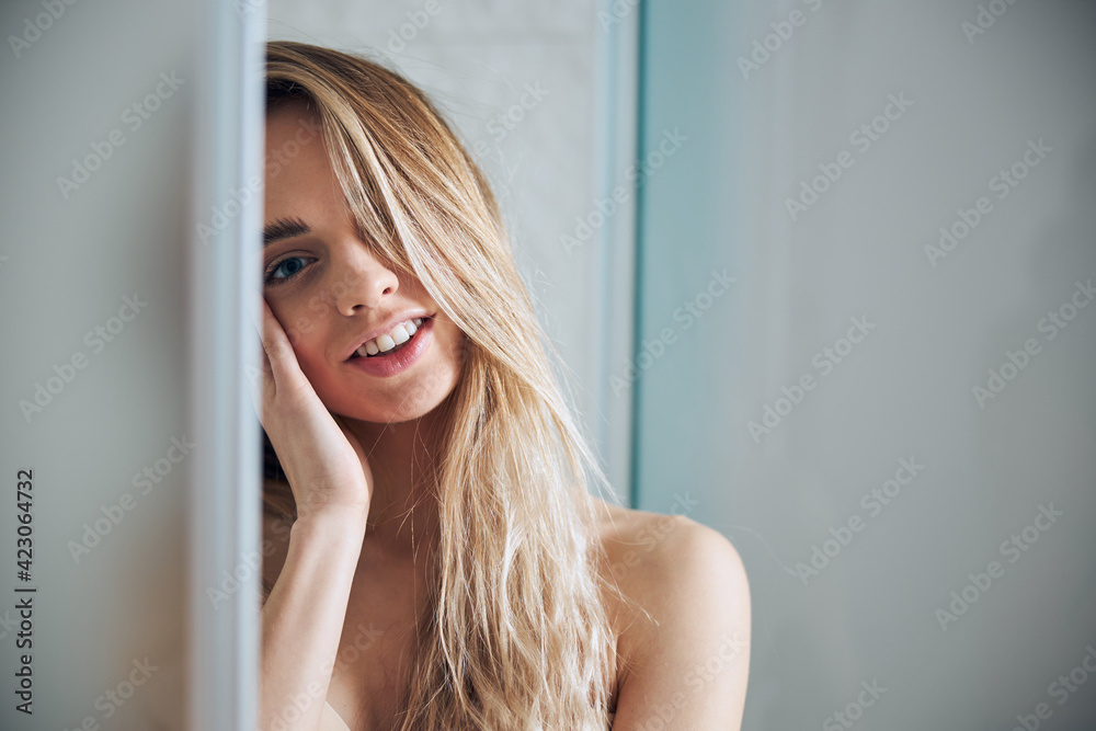 Pleased woman in a bra leaning against the bathroom wall Pleased woman in a bra leaning against the bathroom wall
