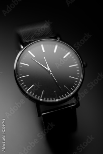 black modern analog wristwatch on a black background